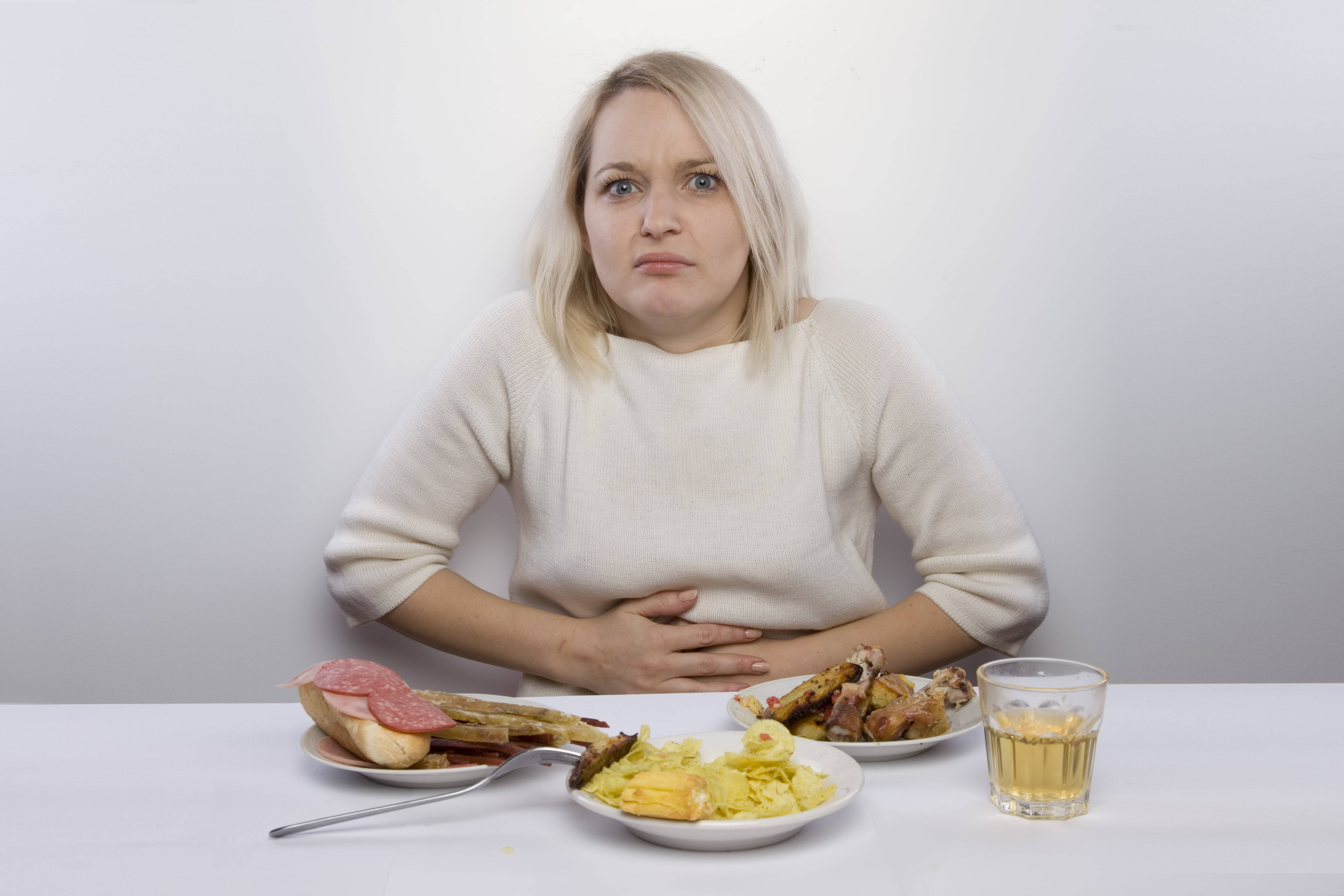 Болит живот и тошнит после еды. Проблемы с пищеварением. Переедание пищи. Еда на женщине. Неправильное питание.